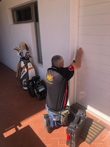 AAA Locksmiths technician working on the front door of a home